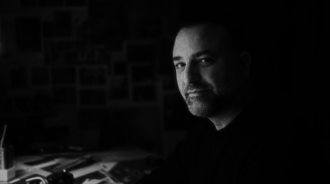 Jody Poole at a worktable in a dim studio, lit by a single lamp