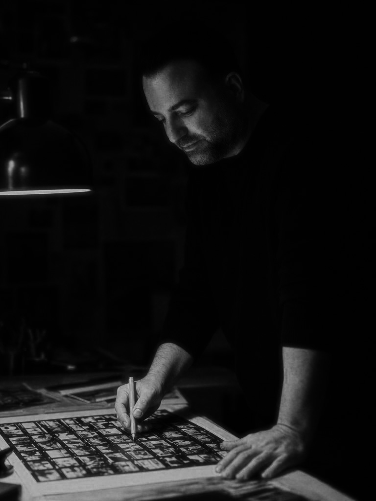 Jody Poole marking up a contact sheet with a red marker under a desk lamp